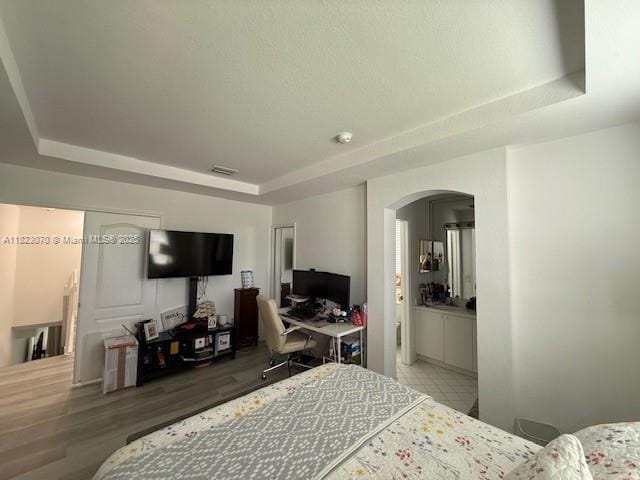 8960 W Flagler St Unit 1, Miami, FL 33174 - bedroom featuring a raised ceiling, arched walkways, an office area, and wood finished floors