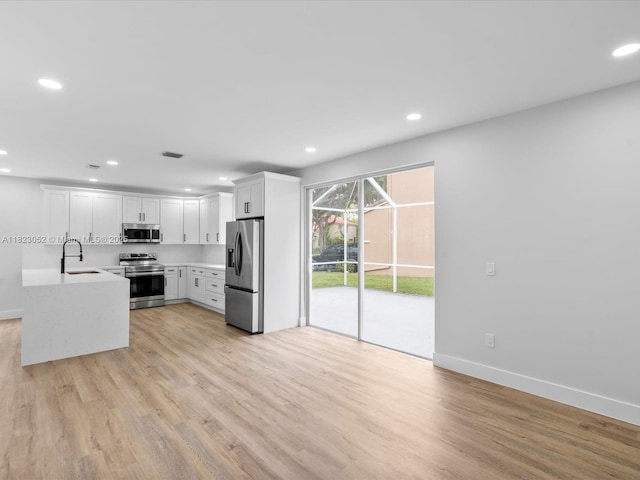 457 NW 87th Ln, Coral Springs, FL 33071 - kitchen with appliances with stainless steel finishes, light wood-style flooring, recessed lighting, light countertops, and white cabinets