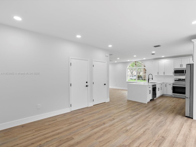 457 NW 87th Ln, Coral Springs, FL 33071 - kitchen with stainless steel appliances, open floor plan, recessed lighting, a peninsula, and light wood-type flooring