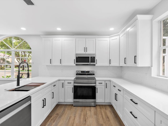 457 NW 87th Ln, Coral Springs, FL 33071 - kitchen featuring stainless steel appliances, white cabinetry, light countertops, tasteful backsplash, and recessed lighting