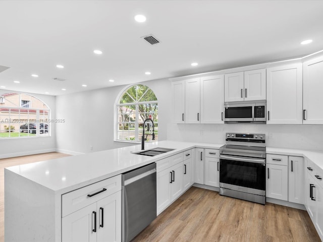 457 NW 87th Ln, Coral Springs, FL 33071 - kitchen with appliances with stainless steel finishes, a peninsula, light wood-style flooring, recessed lighting, and light countertops