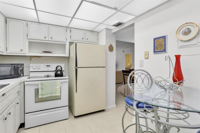 1020 Meridian Ave Unit 616, Miami Beach, FL 33139 - kitchen with white appliances, light tile patterned floors, white cabinetry, light countertops, and open shelves