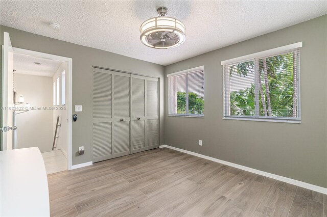 1654 SW 109th Ter, Davie, FL 33324 - unfurnished bedroom with light wood-type flooring, a textured ceiling, and a closet