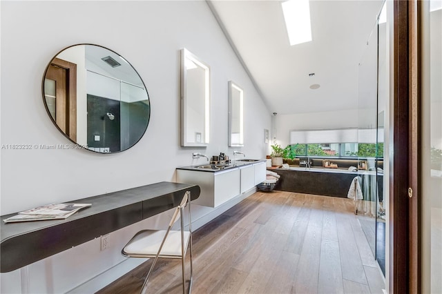 2000 S Bayshore Dr Unit 47, Miami, FL 33133 - bathroom featuring a tub to relax in, wood finished floors, double vanity, and vaulted ceiling