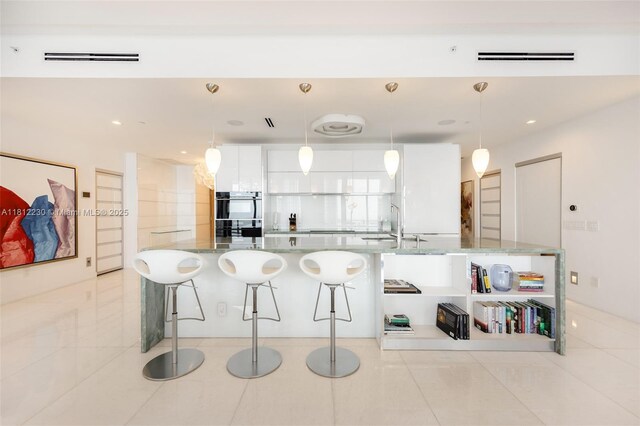 480 NE 31st St Unit 3802, Miami, FL 33137 - kitchen with a breakfast bar area, white cabinets, light tile patterned flooring, recessed lighting, and a spacious island