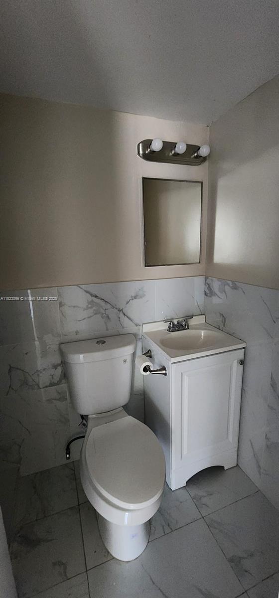 14830 Naranja Lakes Blvd Unit A1B, Homestead, FL 33032 - bathroom featuring tile walls, marble look tile flooring, vanity, and wainscoting