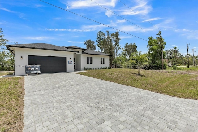 337 Jourferie Rd, Lehigh Acres, FL 33974 - prairie-style house with decorative driveway, a garage, a front lawn, and stucco siding