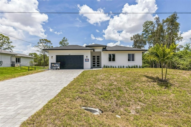 337 Jourferie Rd, Lehigh Acres, FL 33974 - prairie-style house with decorative driveway, stucco siding, an attached garage, and a front lawn