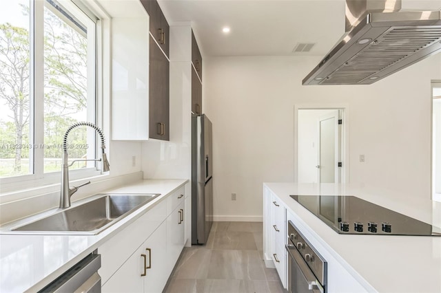 337 Jourferie Rd, Lehigh Acres, FL 33974 - kitchen with stainless steel appliances, wall chimney exhaust hood, healthy amount of natural light, white cabinetry, and recessed lighting