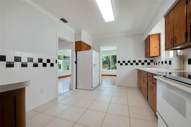 708 Navarre Ave, Coral Gables, FL 33134 - kitchen with white appliances, tile walls, brown cabinets, light tile patterned floors, and crown molding