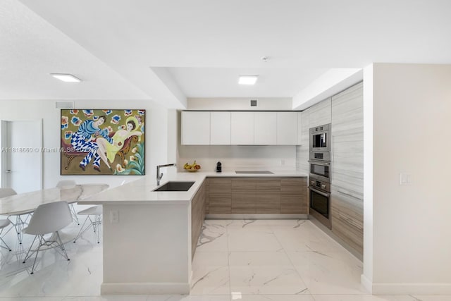 300 Sunny Isles Blvd Unit 4-2303, Sunny Isles Beach, FL 33160 - kitchen with modern cabinets, light marble finish floors, a peninsula, light countertops, and cooktop