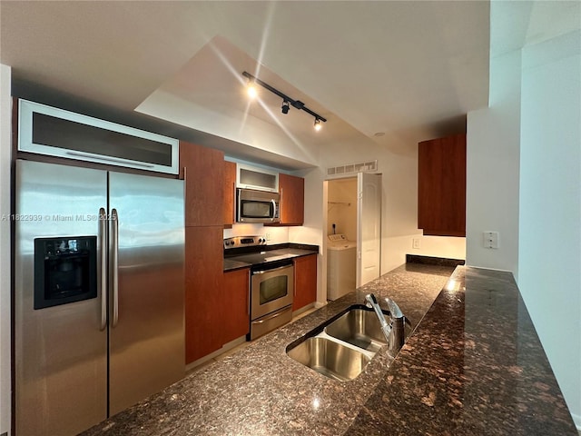 7350 SW 89th St Unit 602S, Miami, FL 33156 - kitchen featuring appliances with stainless steel finishes, washer / dryer, track lighting, brown cabinets, and a peninsula