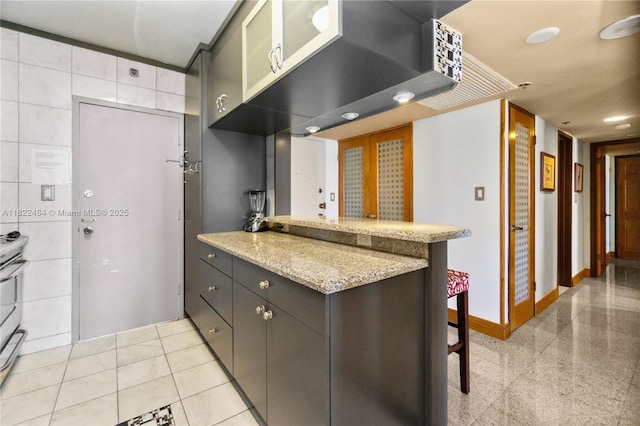 100 Lincoln Rd Unit 811, Miami Beach, FL 33139 - kitchen with a peninsula, a kitchen breakfast bar, glass insert cabinets, light stone counters, and tile walls