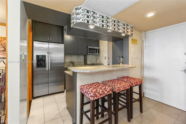 100 Lincoln Rd Unit 811, Miami Beach, FL 33139 - kitchen featuring appliances with stainless steel finishes, dark cabinetry, a kitchen bar, a peninsula, and tasteful backsplash