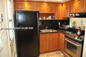 2910 Point E Dr Unit M610, Aventura, FL 33160 - kitchen featuring stainless steel range oven, freestanding refrigerator, range hood, brown cabinetry, and dark countertops