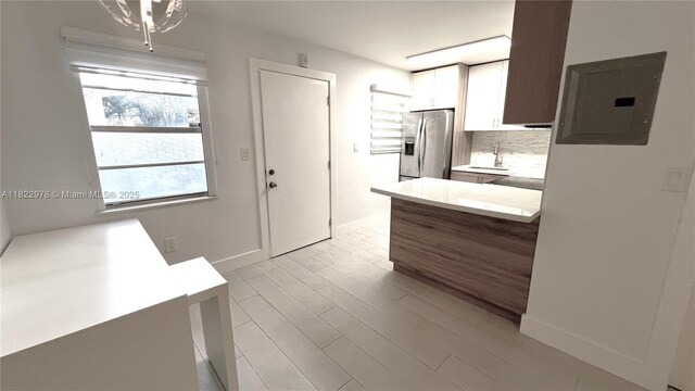 427 Santander Ave Unit 202, Coral Gables, FL 33134 - kitchen featuring stainless steel fridge with ice dispenser, electric panel, light wood-type flooring, backsplash, and white cabinetry