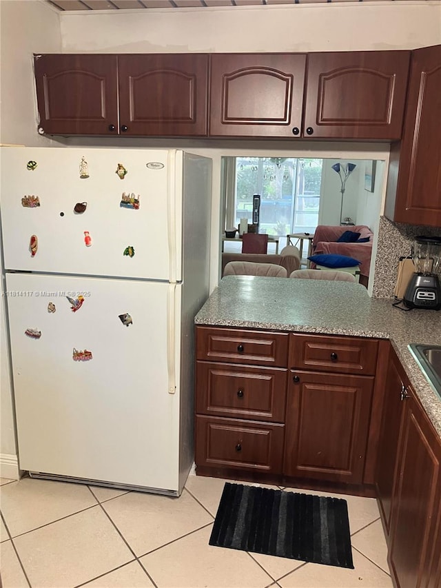 8605 W Sample Rd Unit 101, Coral Springs, FL 33065 - kitchen featuring freestanding refrigerator, light tile patterned floors, a peninsula, dark brown cabinetry, and open floor plan
