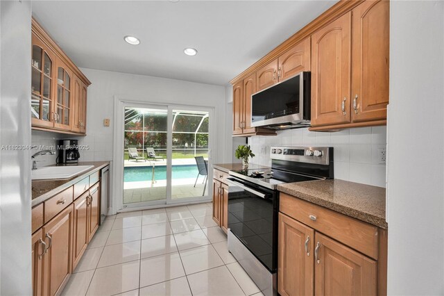 8861 SW 85th St, Miami, FL 33173 - kitchen featuring appliances with stainless steel finishes, backsplash, glass insert cabinets, recessed lighting, and light tile patterned flooring
