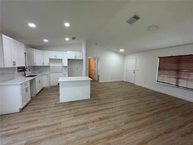 737 SE Brookedge Ave, Port St Lucie, FL 34983 - kitchen featuring a center island, white cabinetry, lofted ceiling, recessed lighting, and light wood-style flooring