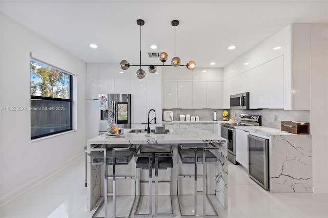 8780 NW 116th Path, Doral, FL 33178 - kitchen with stainless steel appliances, modern cabinets, white cabinetry, wine cooler, and a kitchen breakfast bar