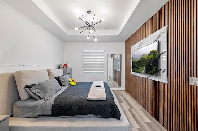 8780 NW 116th Path, Doral, FL 33178 - bedroom featuring a chandelier, a tray ceiling, light wood-type flooring, and wooden walls