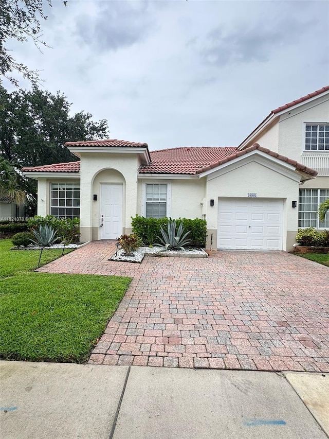 18861 SW 28th Ct, Miramar, FL 33029 - mediterranean / spanish house with a tile roof, decorative driveway, stucco siding, a garage, and a front yard