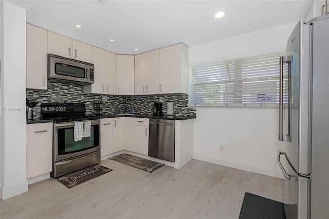 201 Columbus Pkwy, Hollywood, FL 33021 - kitchen featuring appliances with stainless steel finishes, dark countertops, light wood finished floors, backsplash, and recessed lighting