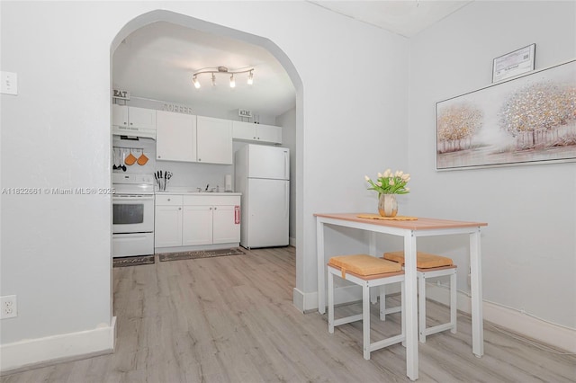 201 Columbus Pkwy, Hollywood, FL 33021 - kitchen with white appliances, arched walkways, white cabinetry, light wood-style floors, and under cabinet range hood