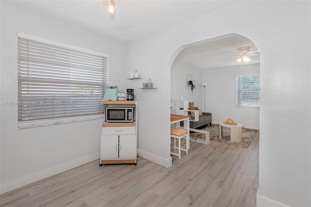 201 Columbus Pkwy, Hollywood, FL 33021 - kitchen with stainless steel microwave, light wood-type flooring, arched walkways, ceiling fan, and white cabinetry