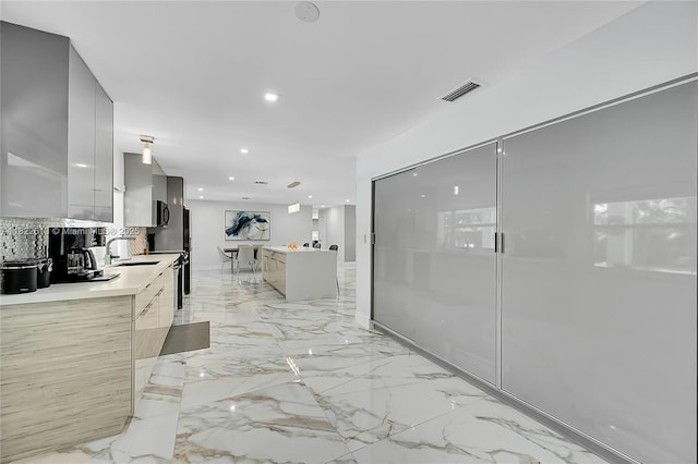 kitchen featuring modern cabinets, light countertops, light marble finish floors, backsplash, and recessed lighting