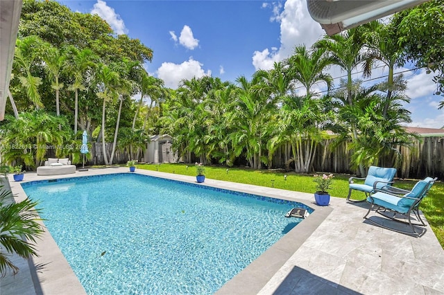 view of pool featuring a fenced backyard, a storage shed, and a patio