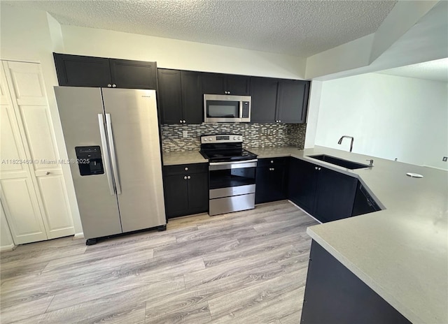 8135 Southgate Blvd, North Lauderdale, FL 33068 - kitchen featuring stainless steel appliances, dark cabinetry, light wood-style floors, light countertops, and a textured ceiling