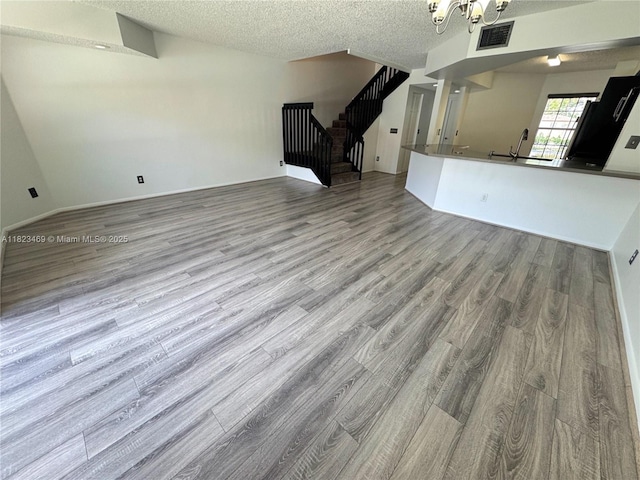 8135 Southgate Blvd, North Lauderdale, FL 33068 - unfurnished living room with wood finished floors, a chandelier, stairs, and a textured ceiling