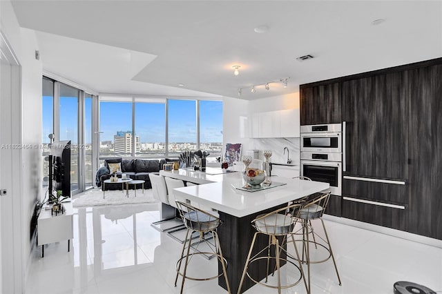 851 NE 1st Ave Unit 2204, Miami, FL 33132 - kitchen featuring stainless steel double oven, a kitchen breakfast bar, modern cabinets, light countertops, and expansive windows
