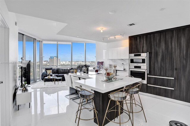 851 NE 1st Ave Unit 2204, Miami, FL 33132 - kitchen featuring stainless steel double oven, a kitchen breakfast bar, modern cabinets, light countertops, and expansive windows
