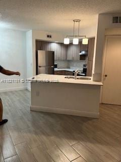 12950 Vista Isles Dr Unit 414, Sunrise, FL 33325 - kitchen with freestanding refrigerator, light countertops, wood finished floors, pendant lighting, and under cabinet range hood