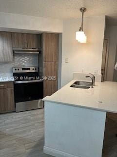 12950 Vista Isles Dr Unit 414, Sunrise, FL 33325 - kitchen featuring stainless steel range, under cabinet range hood, a peninsula, light countertops, and pendant lighting