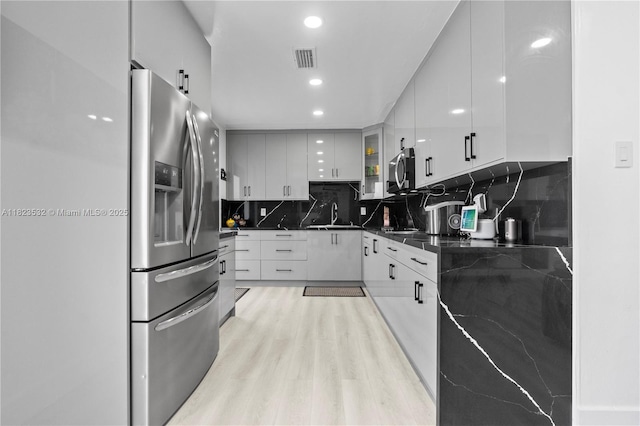 6474 Palm Ave, Hialeah, FL 33012 - kitchen featuring appliances with stainless steel finishes, dark countertops, modern cabinets, backsplash, and light wood finished floors