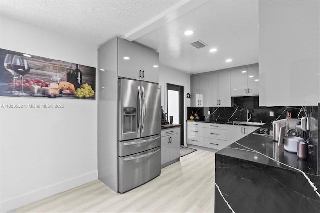 6474 Palm Ave, Hialeah, FL 33012 - kitchen featuring stainless steel fridge with ice dispenser, modern cabinets, light wood-style flooring, backsplash, and a textured ceiling