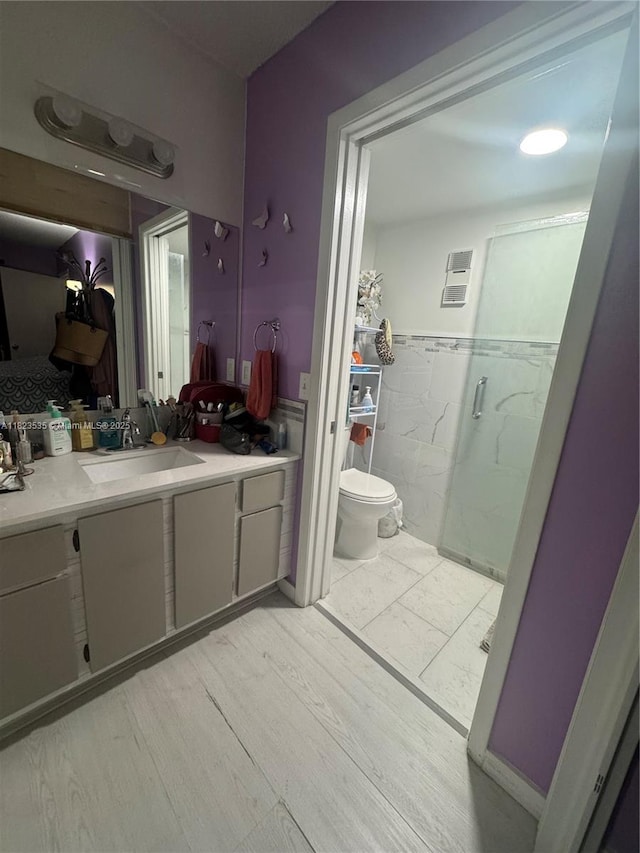 6515 W 27th Ct Unit 49-13, Hialeah, FL 33016 - bathroom featuring a marble finish shower, vanity, wood finished floors, tile walls, and wainscoting