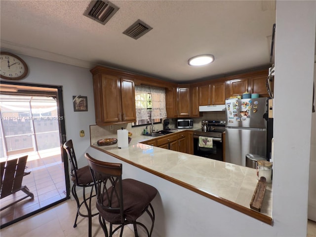1651 SW 120th Ave, Pembroke Pines, FL 33025 - kitchen with stainless steel appliances, under cabinet range hood, a kitchen bar, a textured ceiling, and light countertops