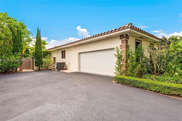 13454 SW 58th Ave, Pinecrest, FL 33156 - view of side of home with stucco siding, asphalt driveway, a garage, a gate, and a tiled roof
