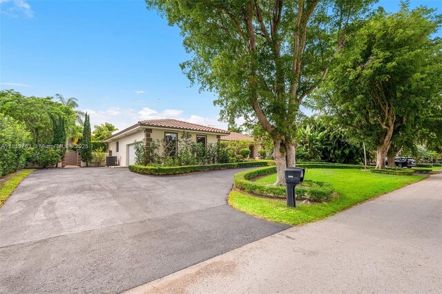 13454 SW 58th Ave, Pinecrest, FL 33156 - mediterranean / spanish house featuring driveway, stucco siding, an attached garage, a front yard, and a tile roof