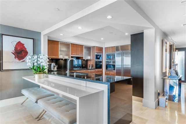 1331 Brickell Bay Dr Unit 2305, Miami, FL 33131 - kitchen with stainless steel appliances, brown cabinetry, modern cabinets, dark stone countertops, and a peninsula