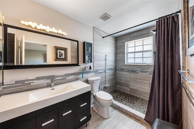 3869 NW 92nd Ave, Sunrise, FL 33351 - bathroom featuring a tile shower, vanity, a textured ceiling, and tile walls