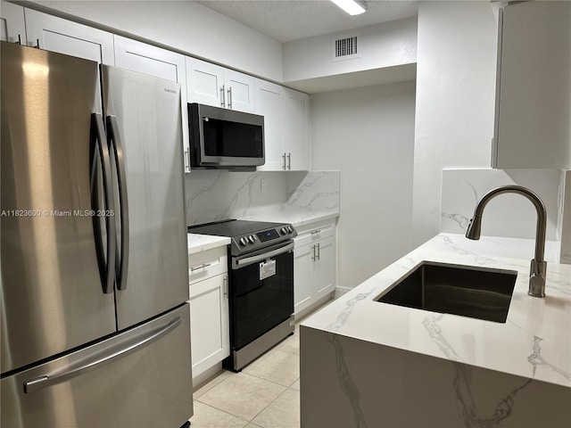 15221 SW 80th St Unit 304, Miami, FL 33193 - kitchen featuring appliances with stainless steel finishes, light stone countertops, tasteful backsplash, white cabinets, and a textured ceiling