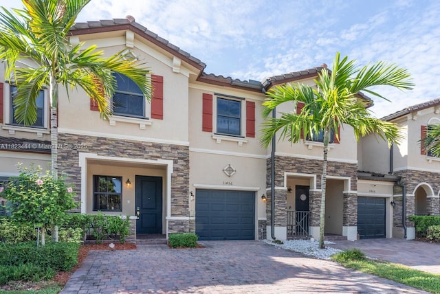 11456 SW 254th St, Homestead, FL 33032 - view of property with stone siding, stucco siding, an attached garage, decorative driveway, and a tiled roof