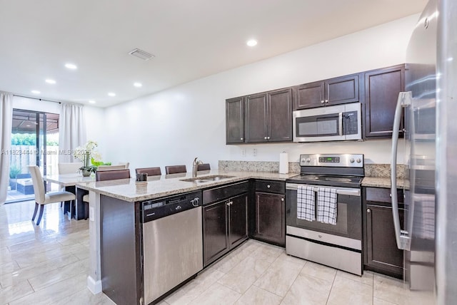 11456 SW 254th St, Homestead, FL 33032 - kitchen with appliances with stainless steel finishes, light stone countertops, a peninsula, dark brown cabinetry, and recessed lighting