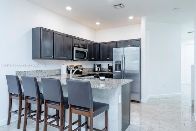 11456 SW 254th St, Homestead, FL 33032 - kitchen with appliances with stainless steel finishes, a peninsula, a breakfast bar, light stone countertops, and recessed lighting