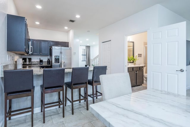 11456 SW 254th St, Homestead, FL 33032 - kitchen with stainless steel refrigerator with ice dispenser, a peninsula, a kitchen bar, light stone counters, and recessed lighting